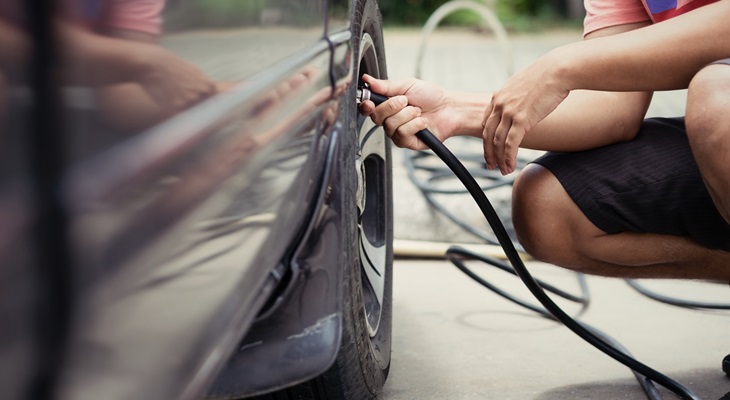 Uomo che controlla pressione gomme automobile 